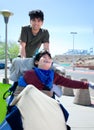 Big brother pushing happy disabled boy in wheelchair