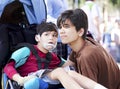 Big brother taking care of disabled little boy in wheelchair