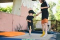 Big brother teaches younger to jump on a trampoline. Children active leisure trampolining holding hands together. Sports weekend