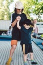 Big brother teaches younger to jump on a trampoline. Children active leisure trampolining holding hands together. Sports weekend