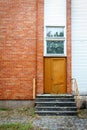 Big brown door on a red brick and white planks wall Royalty Free Stock Photo