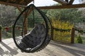 Big brown round rotang chair hanging in wooden outdoor backyard.