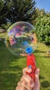 A big bubble made by a red bubble gun in the garden Royalty Free Stock Photo