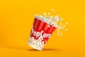 Big bucket of popcorn falling with spilling corns on yellow background Royalty Free Stock Photo