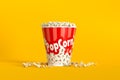 Big bucket of popcorn with spilled corns on yellow background Royalty Free Stock Photo