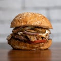 Big burger with grilled meat and vegetables on blurred background. Classic American food. Junk food concept. Homemade