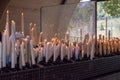 Big burning candles from prayers for hope. Saint Bernadette grotto with many white candles with flame. Sanctuary in Lourdes.