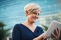 Big business moves on the move. a mature businesswoman using a digital tablet against a city background.