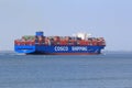 A large blue cargo ship navigates through the sea in summer