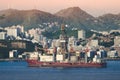 Big cargo ship with city and mountains in background Royalty Free Stock Photo