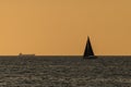 Big cargo ship and small sailing boat on the Baltic Sea. Golden hour Royalty Free Stock Photo