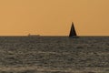 Big cargo ship and small sailing boat on the Baltic Sea. Golden hour Royalty Free Stock Photo