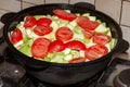 Big cast iron pot, full of vegetables, stewing on stove. Bright red tomatoes and zucchini, vegeterian food, healthy meal concept. Royalty Free Stock Photo