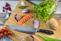 Big chef knife with healthy food - vegetables, onion, salad, potato placed on a cutting board with wood background top view Royalty Free Stock Photo