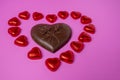 A big chocolate heart and a lot of shiny candy in the shape of hearts wrapped in foil