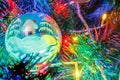 Big christmas ball on the branches of decorative fir in the light of colorful lights of electric garland close-up