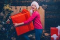 Big Christmas gift. Woman in red Santa hat holding present. Christmas preparation. Luxury girl celebrating New Year. Royalty Free Stock Photo