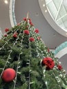 a big christmas tree inside a shopping mall seen from below in perspective, decorated with red balls and a big star at the top, Royalty Free Stock Photo
