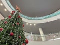 a big christmas tree inside a shopping mall seen from below in perspective, decorated with red balls and a big star at the top, Royalty Free Stock Photo