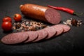 Big chunk of smoked cervelat salami sausage with chili and tomato Royalty Free Stock Photo