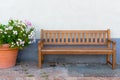 Big clay pot with white and pink flowers and wooden bench against street wall. Gardering design. Patio and relax concept. Royalty Free Stock Photo