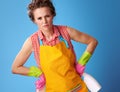 Tense young woman with cleaning sponge and detergent on blue