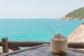 Big coconut with straw on bamboo table overlooking the sea Royalty Free Stock Photo