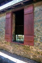 Big colonial wagon seen through open stone barn window with red wooden shutters Royalty Free Stock Photo