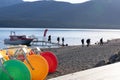 Big colored wheels of peddle boats for hire on lake while tourists disembark on pier in background