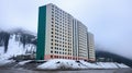 Big colorful condo building on the seaside, near the mountain, in a northern country. Living in harsh climate. Generative AI