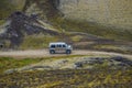 Big crossroad 4WD car is approaching major campsite in colorful rainbow volcanic Landmannalaugar mountains with thousands tourists