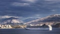 Big cruise ship sails to the sea port of Saranda, Albania. Albanian mountains at the background. Sunset, cloudy sky Royalty Free Stock Photo