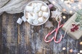 Big cup of cappuccino with marshmallo, candy canes and cookies on brown wooden background with christmas lights. Royalty Free Stock Photo