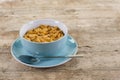 Big cup filled with cornflakes on a wooden table. Royalty Free Stock Photo