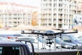 Big custom made drone over picup truck trunk. Heavy UAV hexacopternwith construction site on the background. Commercia