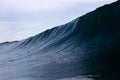 A big, dark, ominous ocean wave looms on a stormy overcast day