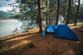 Big dome and camping tent with vestibule. Warm sun rays. Tourist camp among tall pines. Smoke from the fire. Tent. lake shore Royalty Free Stock Photo