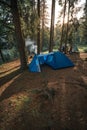 Big dome and camping tent with vestibule. Warm sun rays. Tourist camp among tall pines. Smoke from the fire. Tent. lake shore Royalty Free Stock Photo