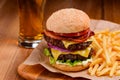 Big double cheeseburger served with handful of French fries and glass of beer Royalty Free Stock Photo