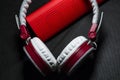 Big earphones of white and red colors. Small the portable speakers. Black background. Modern mobile electronics. Gadgets. Royalty Free Stock Photo