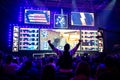 Big esports event. Video games fan on a tribune at tournament`s arena with hands raised. Cheering for his favorite team.