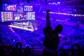 Big esports event. Video games fan on a tribune at tournament`s arena with hands raised. Cheering for his favorite team. Royalty Free Stock Photo