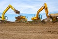 Big excavators are loading two trucks with ground on building site Royalty Free Stock Photo