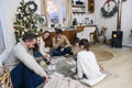 Big family with children sitting on floor near Xmas tree playing lotto board game together