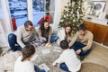 Big family with children sitting on floor near Xmas tree playing lotto