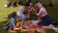 Big family having fun on picnic in city park. They interact with friend. Royalty Free Stock Photo