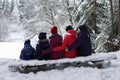 Big family, parents and three children are sitting on a bench in a snowy forest bench Royalty Free Stock Photo