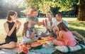 Big family sitting on the picnic blanket in a city park during weekend Sunday sunny day. They are smiling, chatting, laughing and Royalty Free Stock Photo