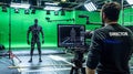 Big film studio, professional crew shooting blockbuster movie. Using green screen with actor wearing motion tracking Royalty Free Stock Photo