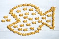 Big fish eats little fishes abstract concept illustrated with small crispy cookies on white wooden background